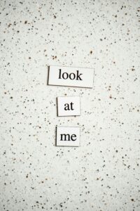 Minimalist text design with "look at me" on speckled surface, perfect for conceptual themes.